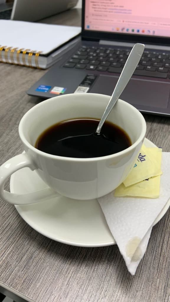 Cup of black coffee next to an office laptop